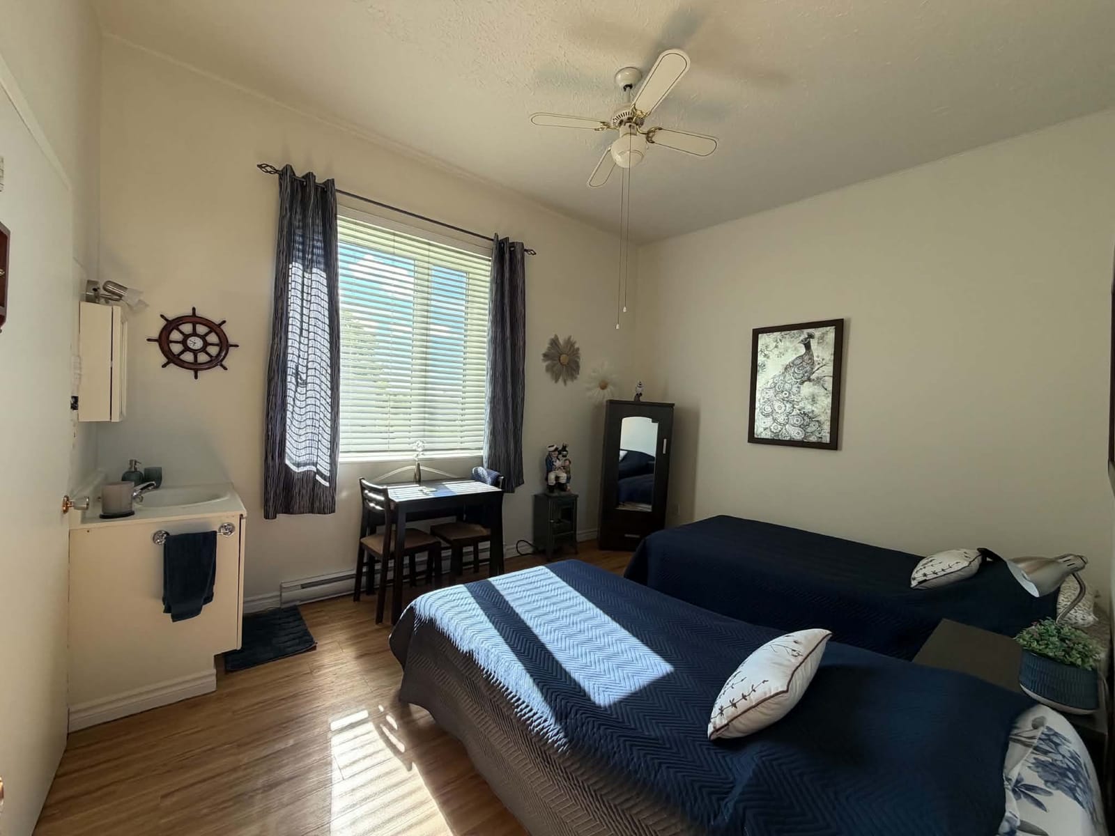 Chambre avec deux lits simples, table de travail et lavabo