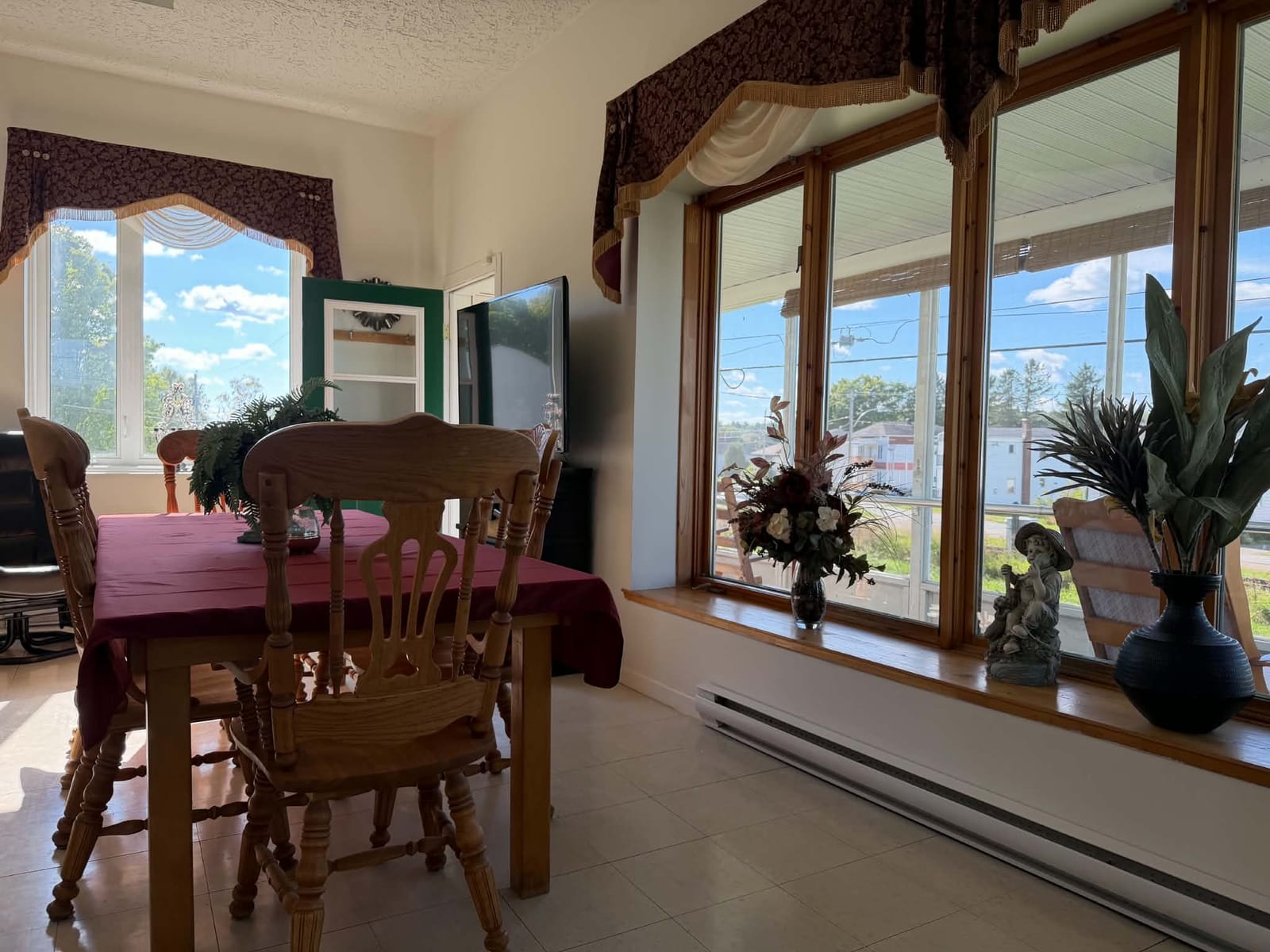 Salle à manger commune avec grande table et fenêtres donnant sur la véranda